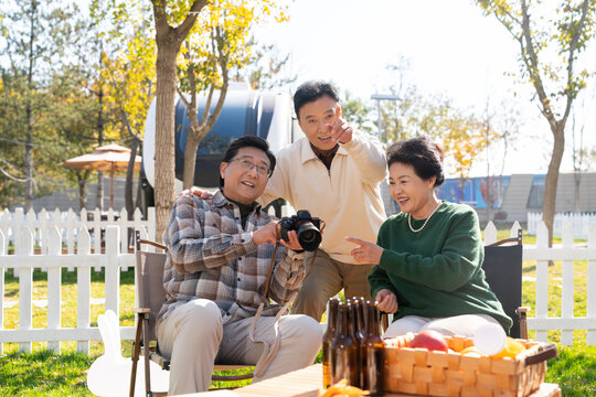 一群中老年人坐在露营地看数码相机