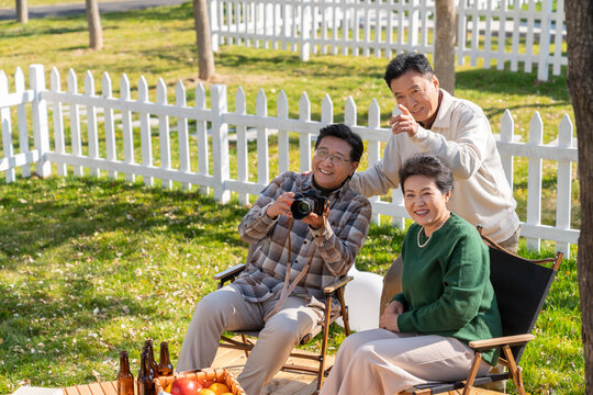 一群中老年人坐在露營(yíng)地看數(shù)碼相機(jī)
