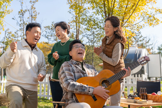 一群中老年人在房车露营地弹吉他唱歌