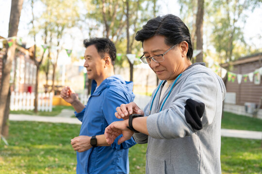 两戴运动手表的中老年男人在树林里跑步健身