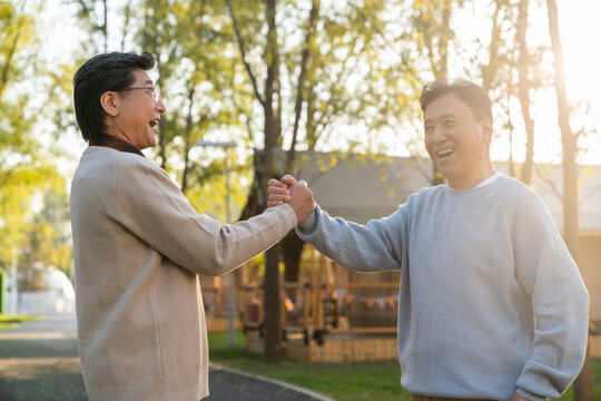 两个中老年男人开心地握手