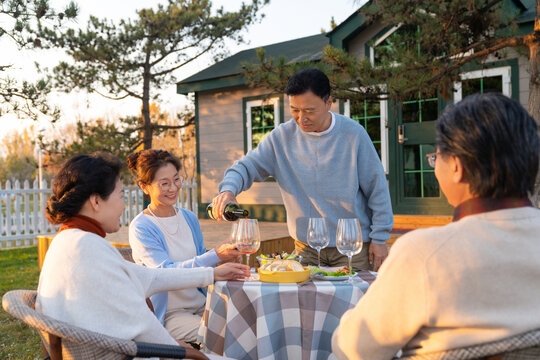 夕阳下中老年朋友在庭院里聚会喝酒聊天