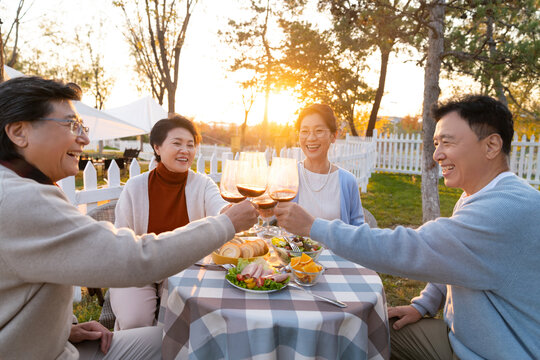 夕阳下中老年朋友在庭院里聚会喝酒聊天