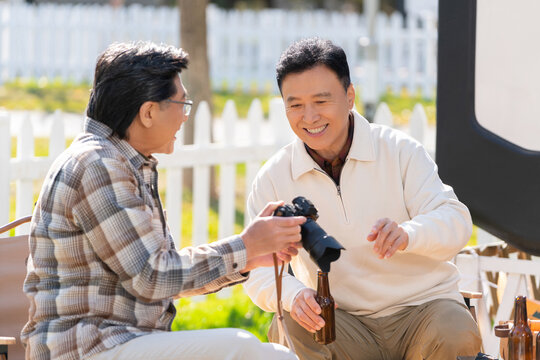 两个老年男人坐在露营地看数码相机