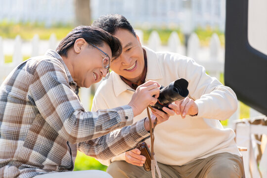 两个老年男人坐在露营地看数码相机