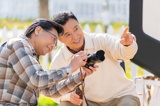 两个老年男人坐在露营地看数码相机