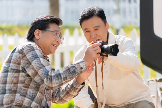 两个老年男人坐在露营地看数码相机