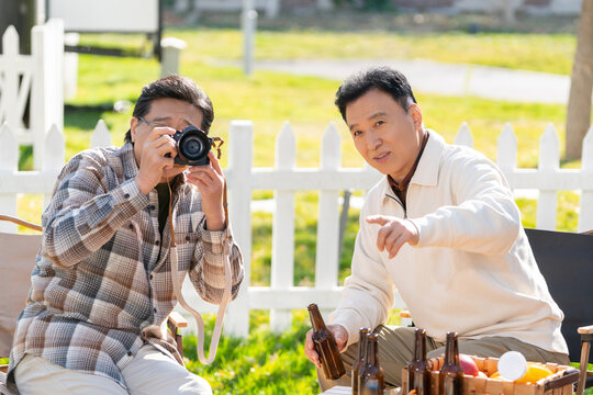 两个老年男人坐在露营地看数码相机