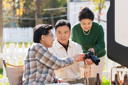 一群中老年人坐在露营地看数码相机