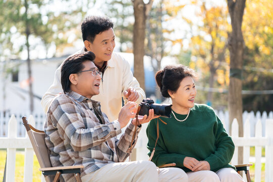 一群中老年人坐在露營(yíng)地看數(shù)碼相機(jī)