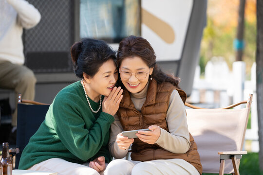 两个老年人女人坐在露营地聊天看手机视频