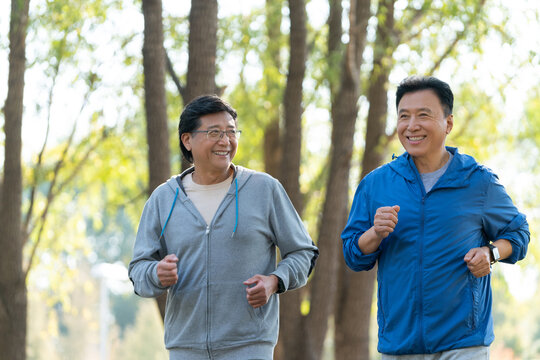 两个戴运动手表的中老年男人在树林跑步健身
