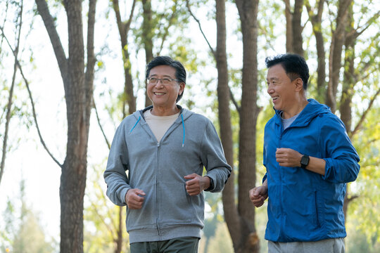 两个戴运动手表的中老年男人在树林跑步健身