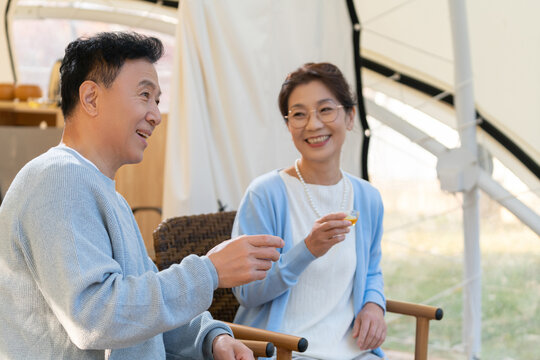 老年夫妻在露营地坐着摇椅喝茶聊天