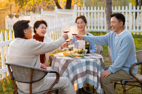 夕阳下中老年朋友在庭院里聚会喝酒聊天