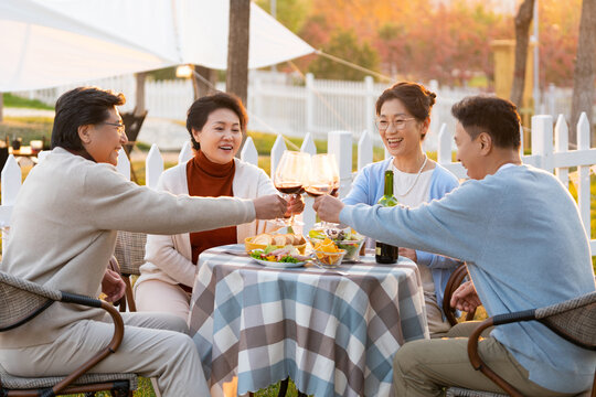 夕阳下中老年朋友在庭院里聚会喝酒聊天