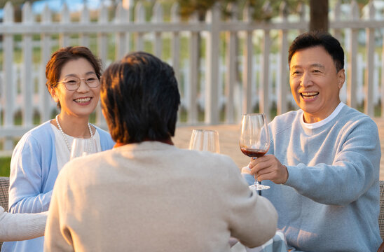 夕阳下中老年朋友在庭院里聚会喝酒聊天