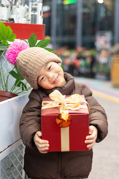 一个小男孩抱着红色礼盒