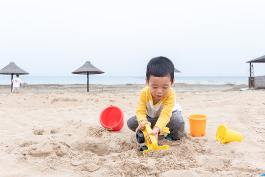 快乐的小男在海边玩沙子