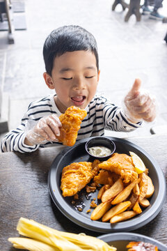 小男孩满足地吃炸鸡薯条