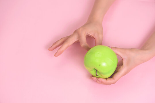 手拿绿苹果创意粉色背景
