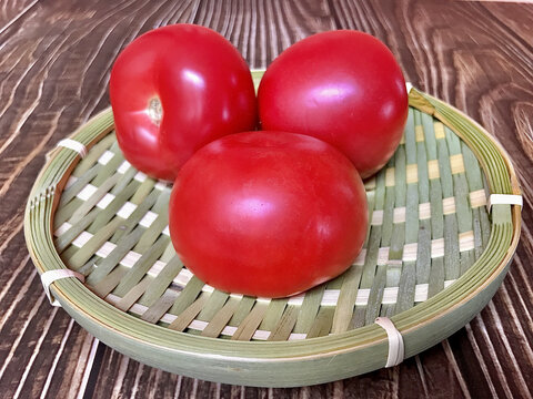 木纹桌子上竹篮里的番茄西红柿