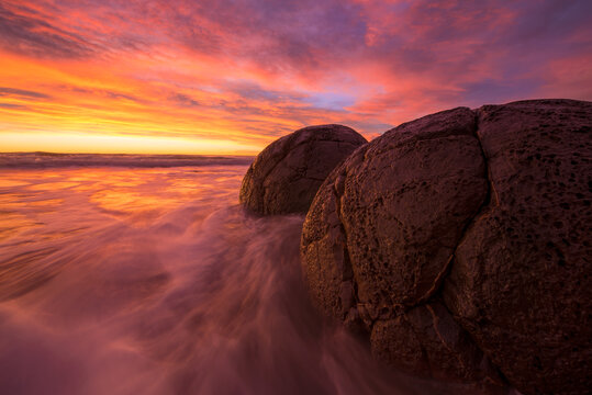 日落时的海滩边的巨石