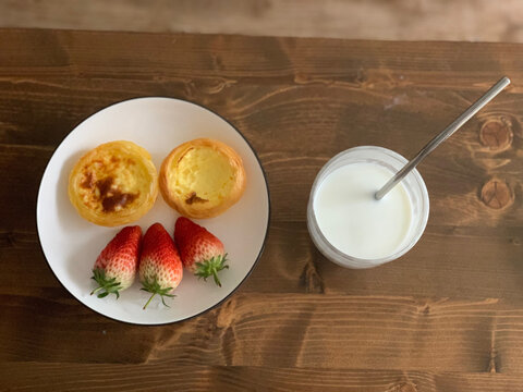 早餐是蛋挞草莓和一杯牛奶