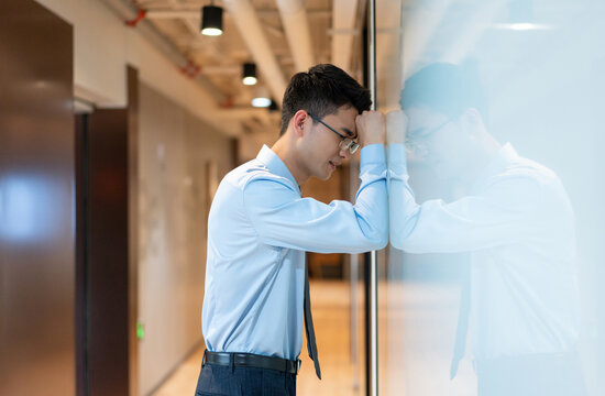 商务人士生气地靠在走廊墙上