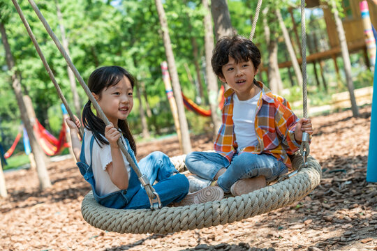 两个小孩子面对面开心荡秋千