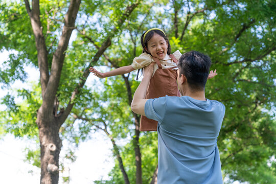 爸爸抱起女儿张开双臂转圈旋转