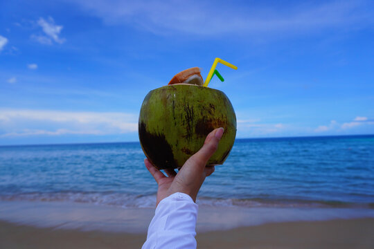 沙滩边手捧椰子特写