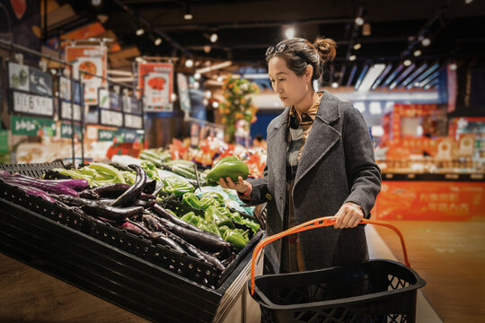亚洲女性超级市场挑选有机蔬菜