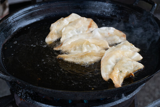 黑色煎锅里的几个煎饺常德锅饺