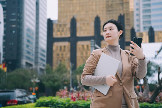 职业女性手拿电脑行走在户外