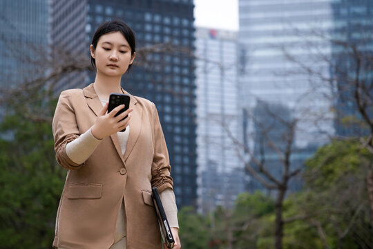 年轻女商人在户外浏览手机