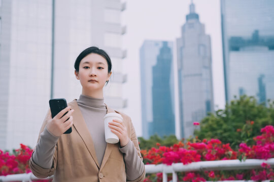 自信的女商人带着咖啡和电话走路