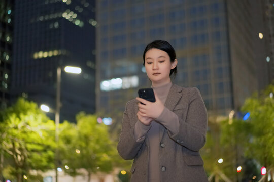 在户外城市夜里自信女心查看手机