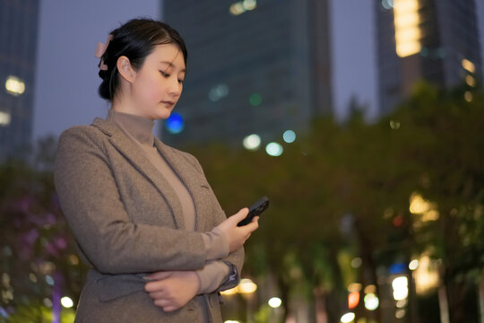 城市夜晚街道上职业女性查看手机