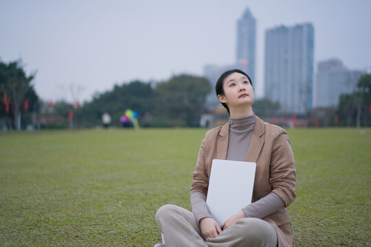 坐在公园里手拿电脑的自信女性