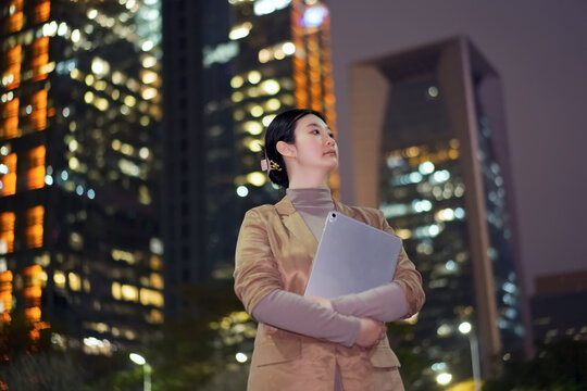 在城市夜里手拿电脑的职业女性