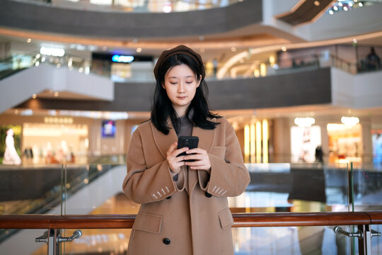 年轻女性在商场专注手机发短信