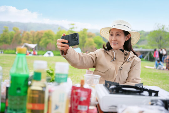户外草地宿营的女性用手机拍照