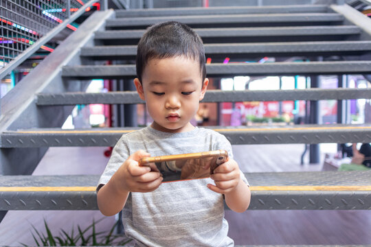 一个小男孩坐着玩手机