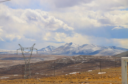 蓝天白云下的高架电力和远处雪山