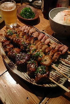 一盤美味的烤雞肉串，配上一杯啤酒和一碗米飯