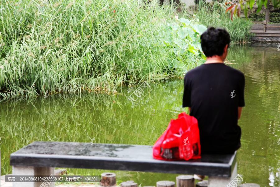 坐在河边石条凳上的人物背影