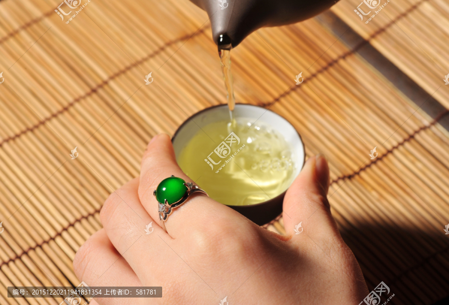 手戴绿色玉石戒指倒茶
