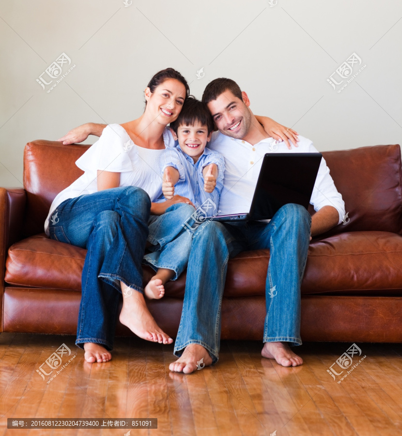 在沙发上一起玩电脑的一家人