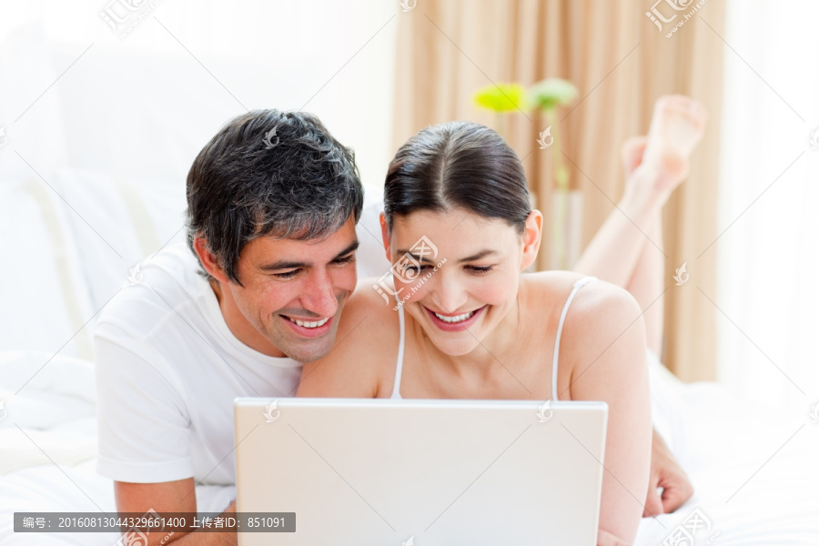 在床上用电脑的夫妇